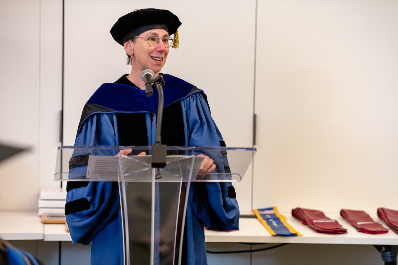 Graduate Dean Aimee Surprenant in academic regalia standing at a podium