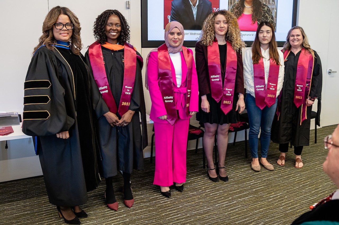 Six women standing in a row wearing recognition stoles